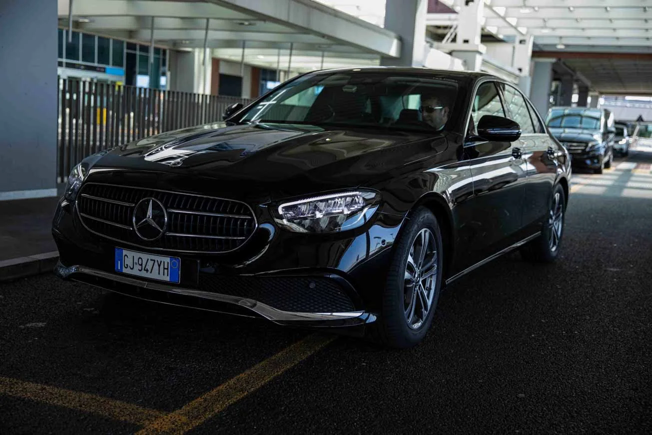 Berlina Mercedes Classe E nera, frontale, aeroporto — servizio NCC Berlina Mercedes Classe E nera, frontale, aeroporto — servizio NCC